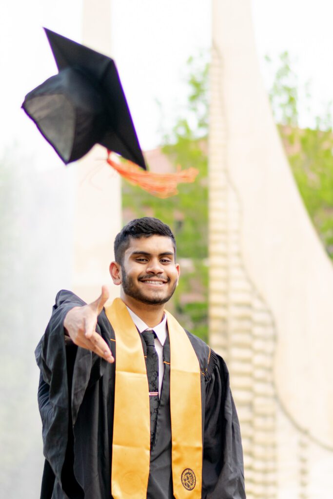 Purdue University grad photo tossing cap in front of engineering fountain